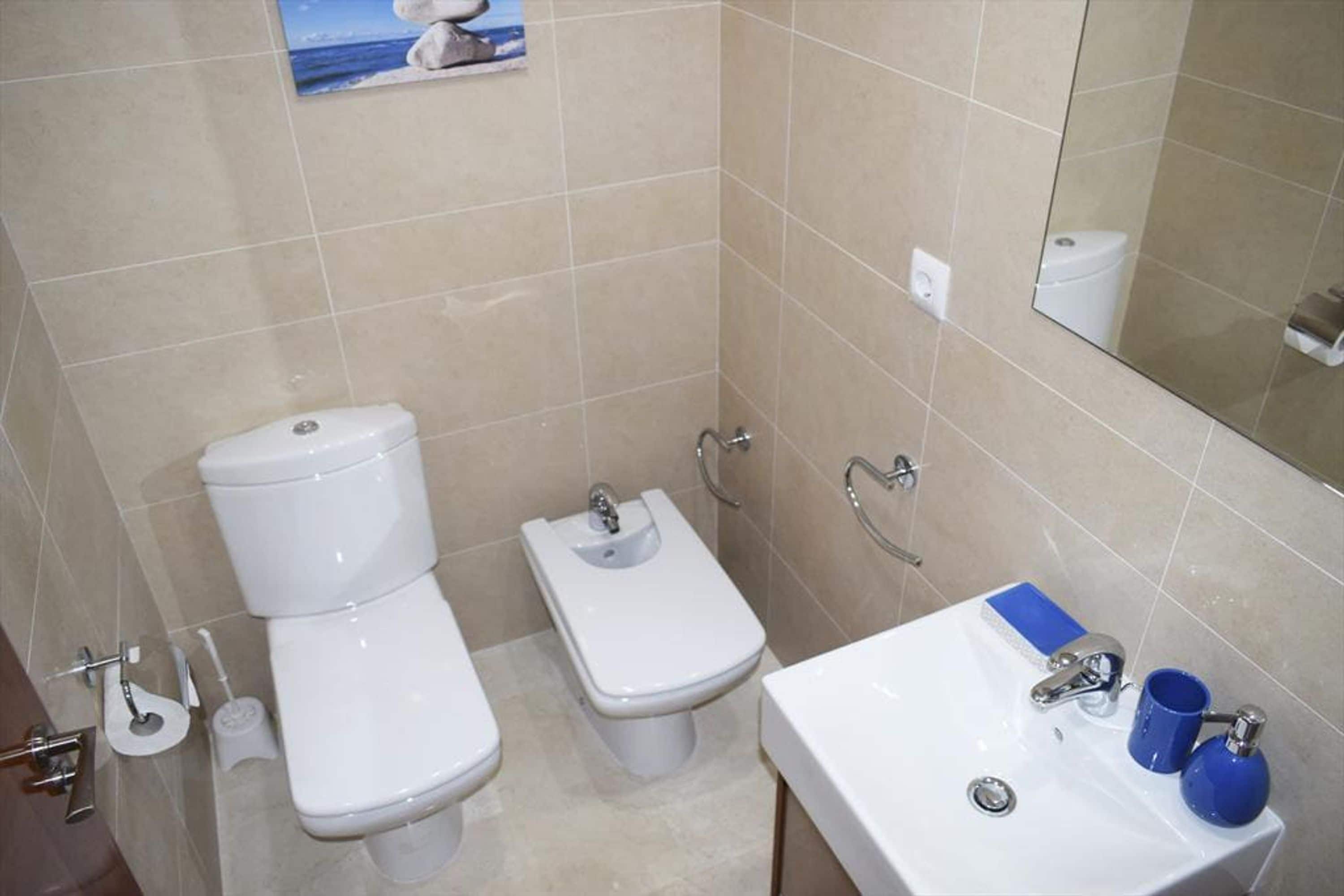 Une salle de bain équipée de toilettes, d’un bidet et d’un lavabo.