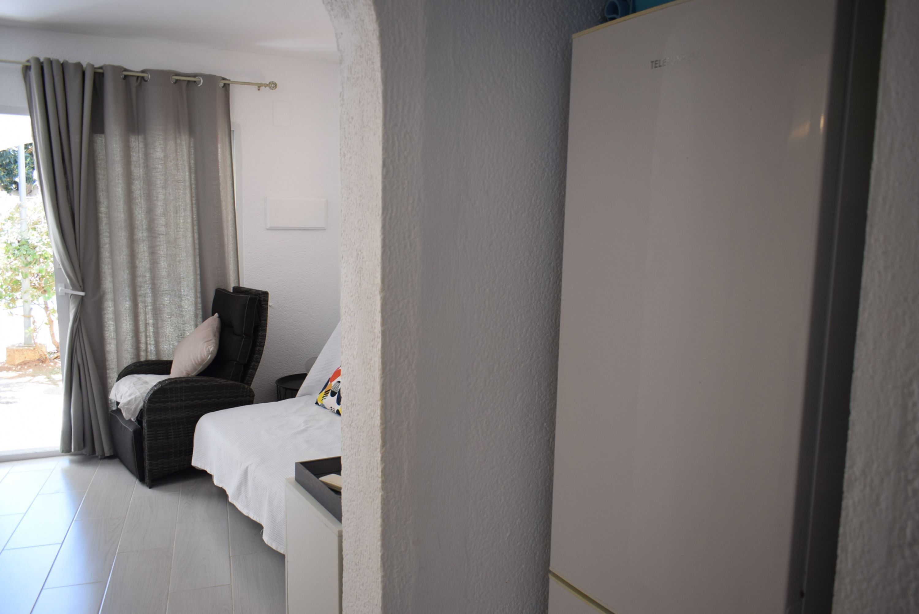 Une chambre avec un lit, une chaise, une armoire et une vue sur l’extérieur.