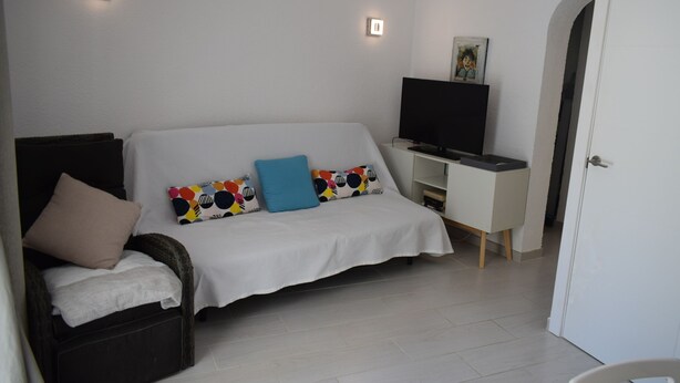 A bedroom with a bed, a desk, a television, and a door. - Pb1116 in Denia With 1 Bedrooms and 1 Bathrooms (Denia)
