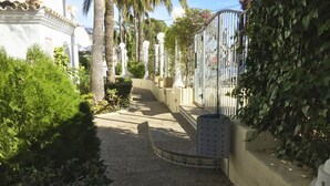 En smal sti omkranset af frodig vegetation og en hvid bygning med udsmykket facade.