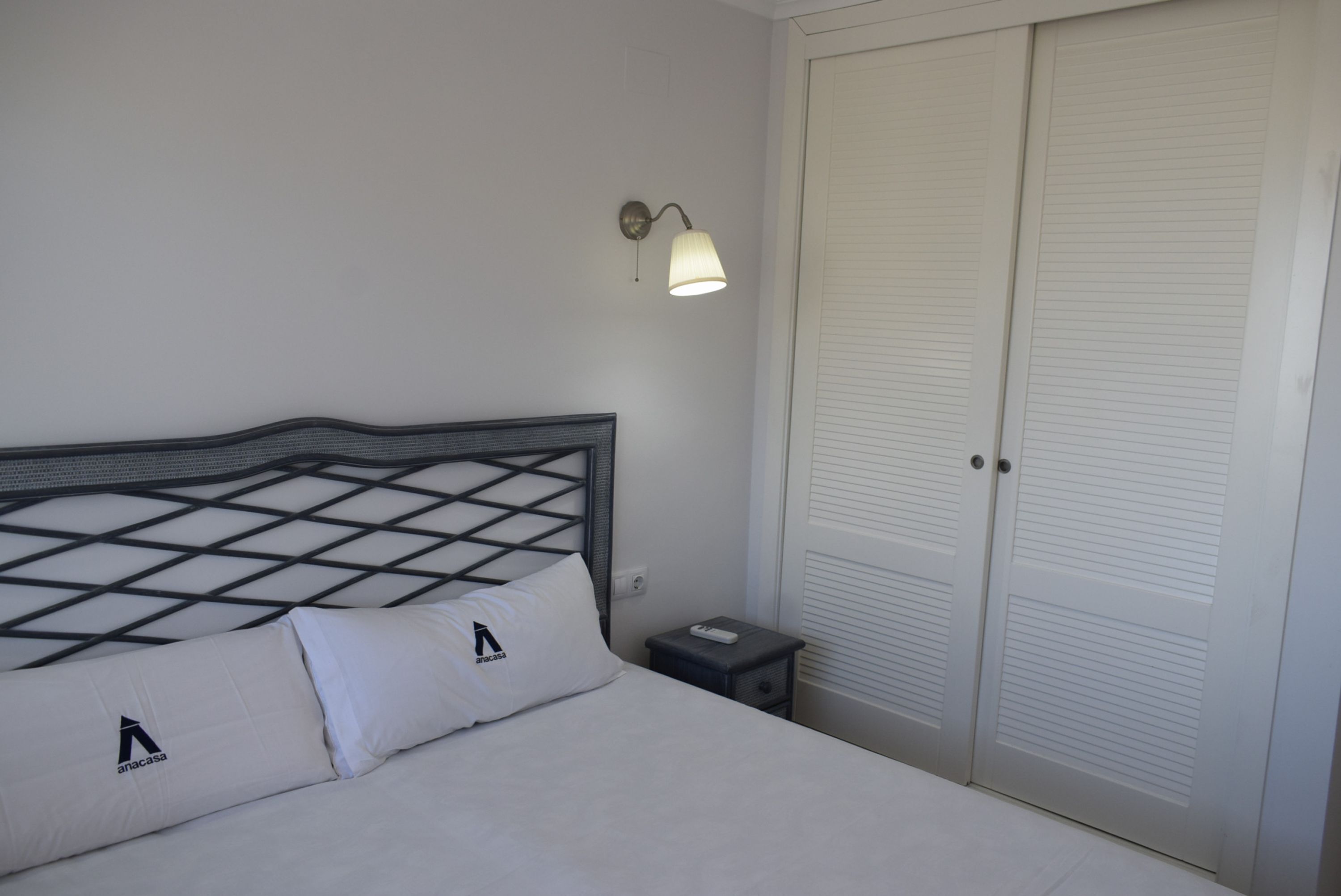 A hotel room with a bed, a nightstand, a lamp, and a closet.
