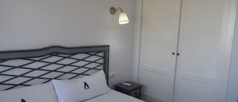 A hotel room with a bed, a nightstand, a lamp, and a closet.