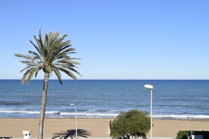 Ein Strand mit einer Palme, einer Straßenlaterne und freiem Blick auf das Meer.