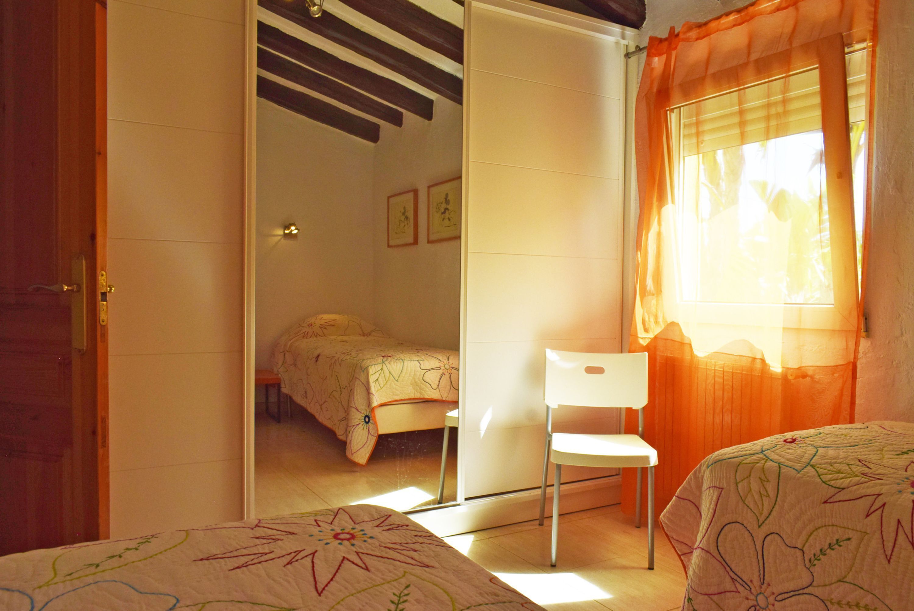 A bedroom with a bed, a chair, and a wardrobe.