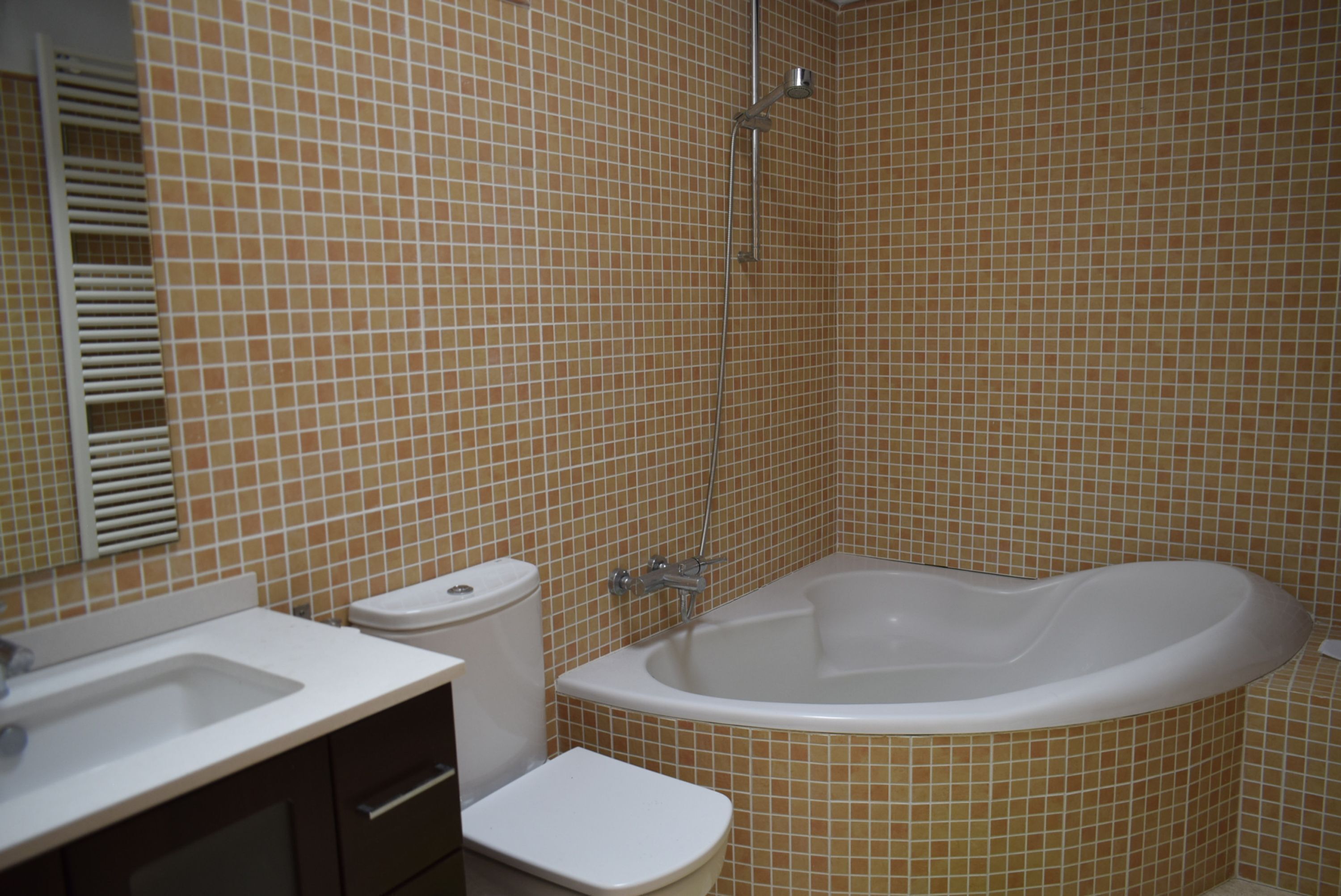 A bathroom with a bathtub, toilet, sink, and tiled walls.
