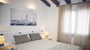 A neatly made bed with striped pillows, a bedside lamp, and a painting of sailboats on the wall. - Ch3400 in Denia With 3 Bedrooms and 2 Bathrooms (Denia)