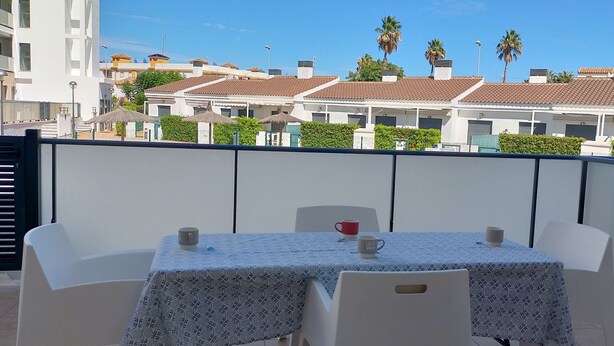 Un balcone con due tavoli, ognuno con una tovaglia e una tazza.