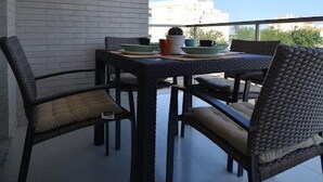 A balcony with a table and chairs, a white brick wall, and a clear blue sky. - Ap625 in Oliva With 2 Bedrooms and 2 Bathrooms (Oliva)