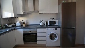 A compact kitchen with a built-in oven, microwave, and washing machine. - Ap625 in Oliva With 2 Bedrooms and 2 Bathrooms (Oliva)