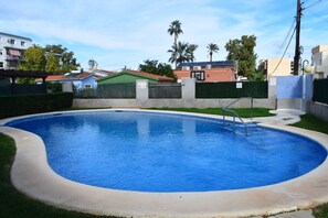 A swimming pool with a curved edge, surrounded by a low wall and a small grassy area. - Ap2213 in Denia With 2 Bedrooms and 2 Bathrooms (Denia)
