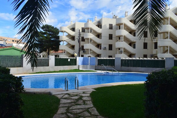 A residential building with a swimming pool, surrounded by well-maintained lawns and palm trees. - Ap2213 in Denia With 2 Bedrooms and 2 Bathrooms (Denia)