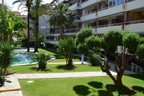 Ein Innenhof mit Schwimmbecken, Palmen und einem gepflasterten Weg.