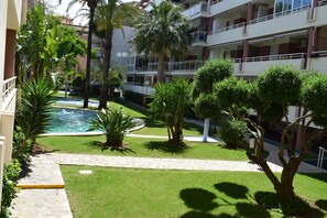 Ein Innenhof mit Swimmingpool, Palmen und einem gepflasterten Weg.