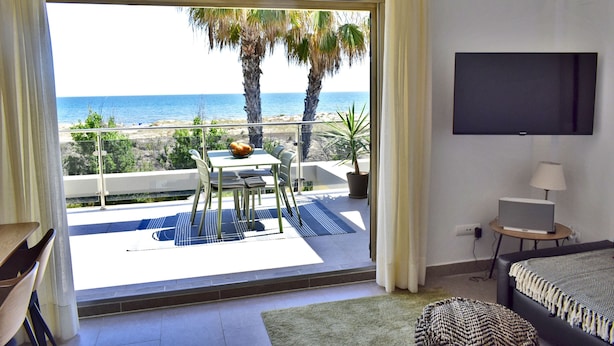 A room with a balcony overlooking the sea, a bed, a TV, and a dining area with a table and chairs. - Dup3291 in Oliva With 3 Bedrooms and 2 Bathrooms (Oliva)