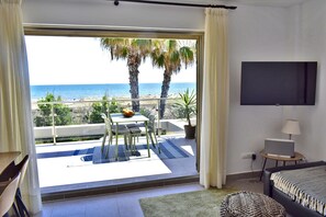 A room with a balcony overlooking the sea, a bed, a TV, and a dining area with a table and chairs. - Dup3291 in Oliva With 3 Bedrooms and 2 Bathrooms (Oliva)