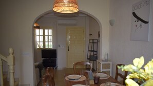 A dining area with a wooden table set for four, a television in the background, and a door leading to another room. - Dup2135 in Denia With 2 Bedrooms and 1 Bathrooms (Denia)