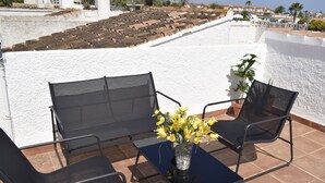 A terrace with a table and two chairs, a vase with yellow flowers, and a potted plant. - Dup2135 in Denia With 2 Bedrooms and 1 Bathrooms (Denia)