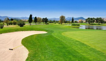 A golf course with a sand bunker, water hazards, and a pond.