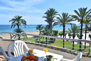 A balcony with a table set for breakfast, overlooking a beach with palm trees and the ocean. - Ap3208 in Denia With 3 Bedrooms and 2 Bathrooms (Denia)