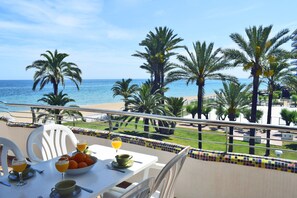 A balcony with a table set for breakfast, overlooking a beach with palm trees and the sea. - Ap3208 in Denia With 3 Bedrooms and 2 Bathrooms (Denia)