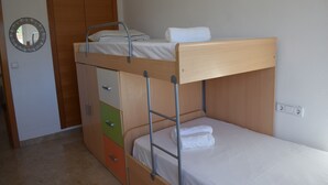 Un lit superposé avec une tête de lit en bois, un miroir et une armoire dotée de plusieurs tiroirs.