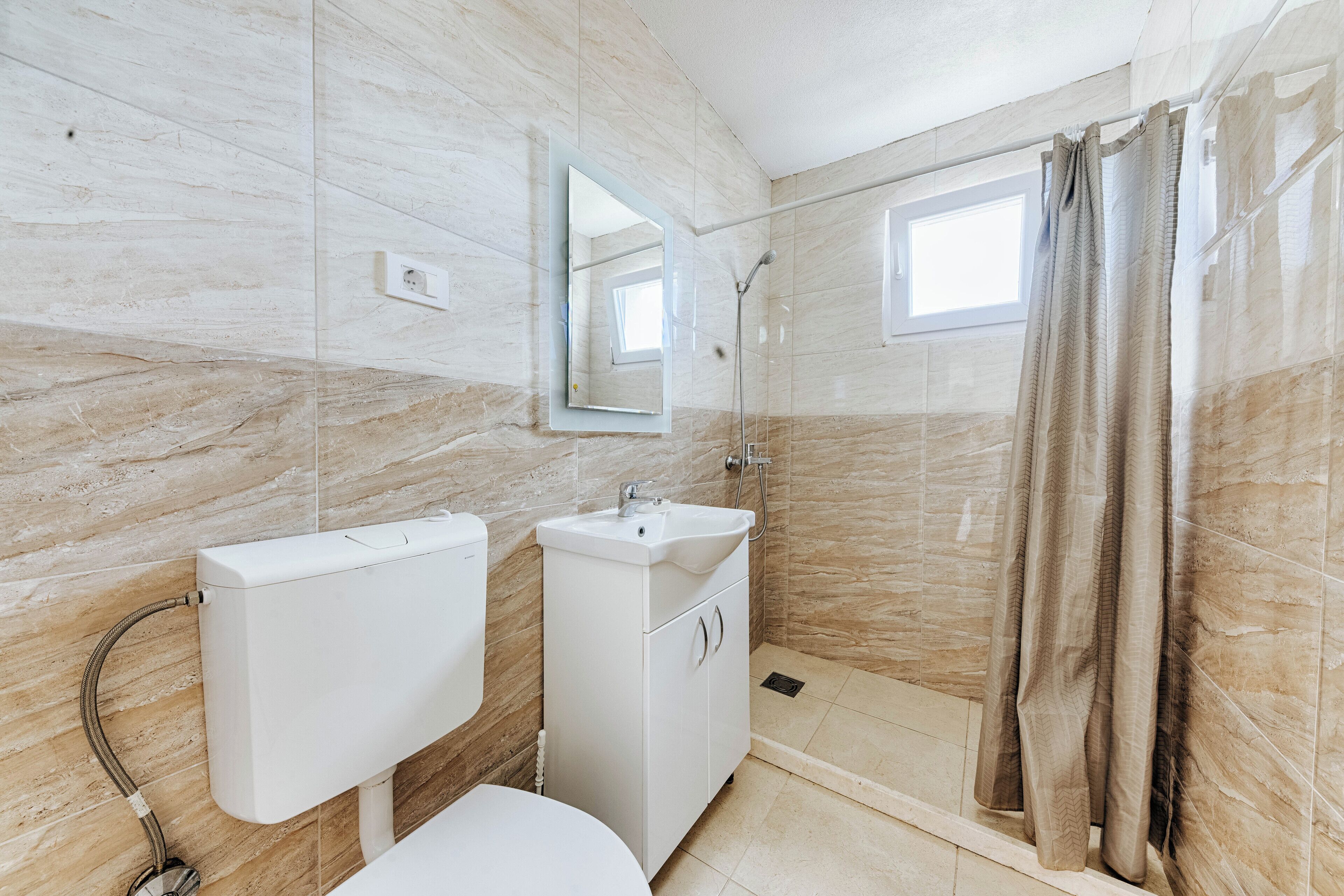 A bathroom with a toilet, sink, and shower.