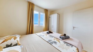 Ett hotellrum med två sängar, en garderob och ett fönster med gardiner.