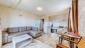 A modern living room with a sofa, a coffee table, and a dining area with chairs.