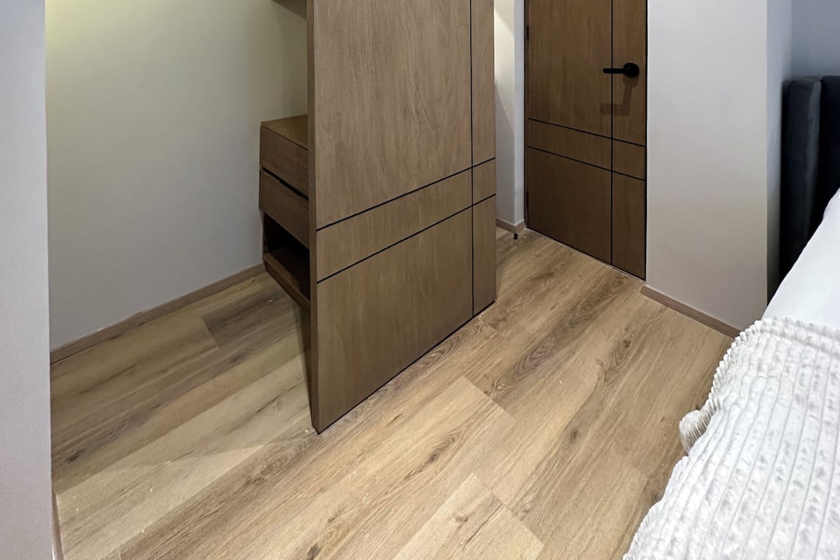 A bedroom with a sliding wardrobe, a bedside table, and a bed.