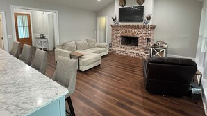 A living room with a fireplace, a sofa, a dining table, and chairs. - AUGUSTA MASTERS RENTAL_Spacious 5-bedroom house in fantastic Appling (Appling)