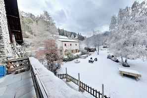 A snow-covered courtyard with a bench, a wooden fence, and a building with a sloped roof. - CASA-Blizzard 2 chambres apt à Saint-Véran (Molines-en-Queyras)