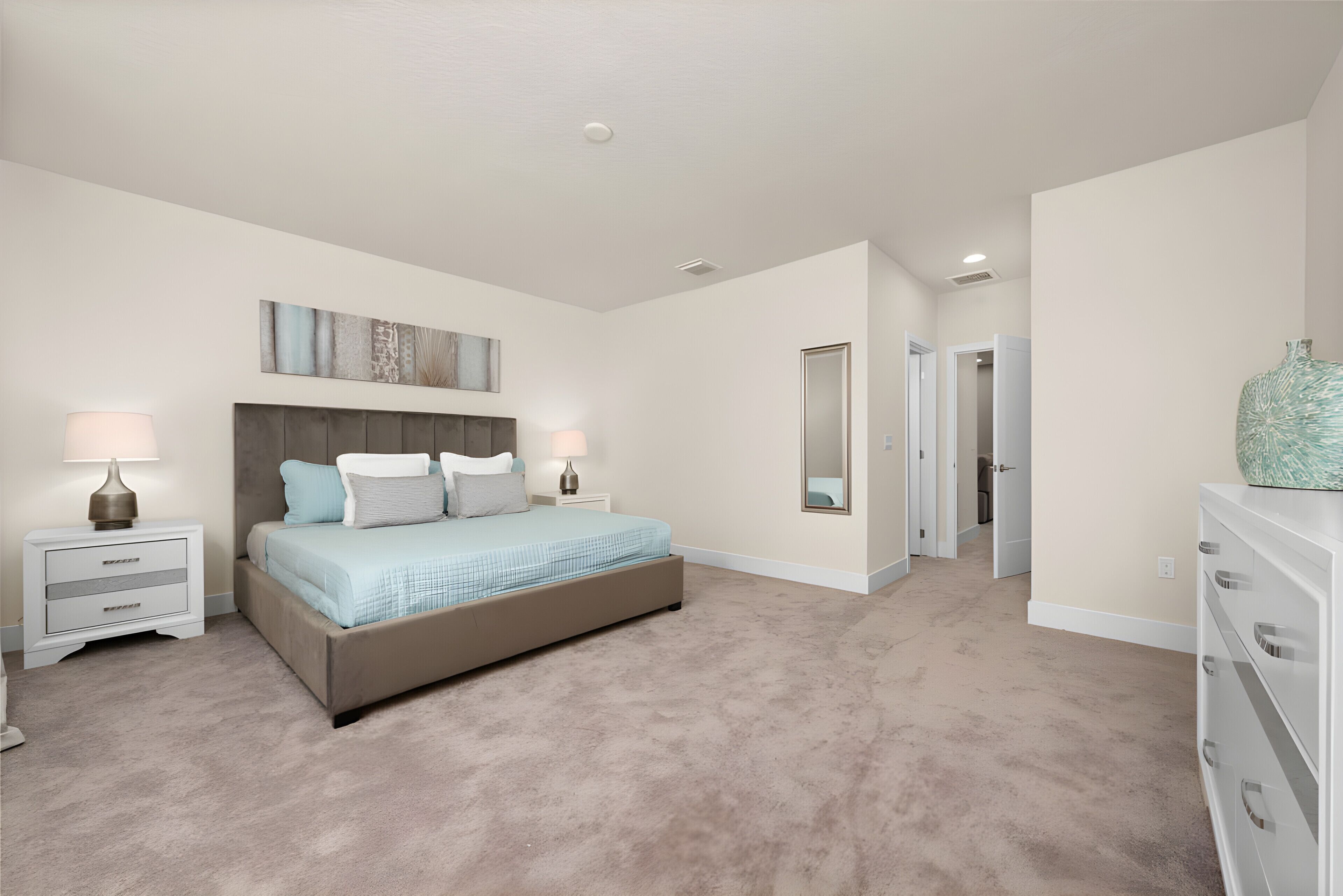 A bedroom with a large bed, nightstands, a dresser, and a mirror.