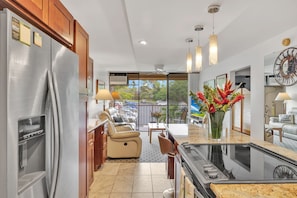 A modern kitchen with a built-in refrigerator, a dining area with a table and chairs, and a view of the outside. - Location, Location!  Walking distance to beach, restaurants, and shops! (Kihei)