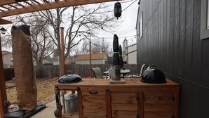 Une cuisine extérieure en bois équipée d’un barbecue, d’une machine à café et d’un meuble de rangement.