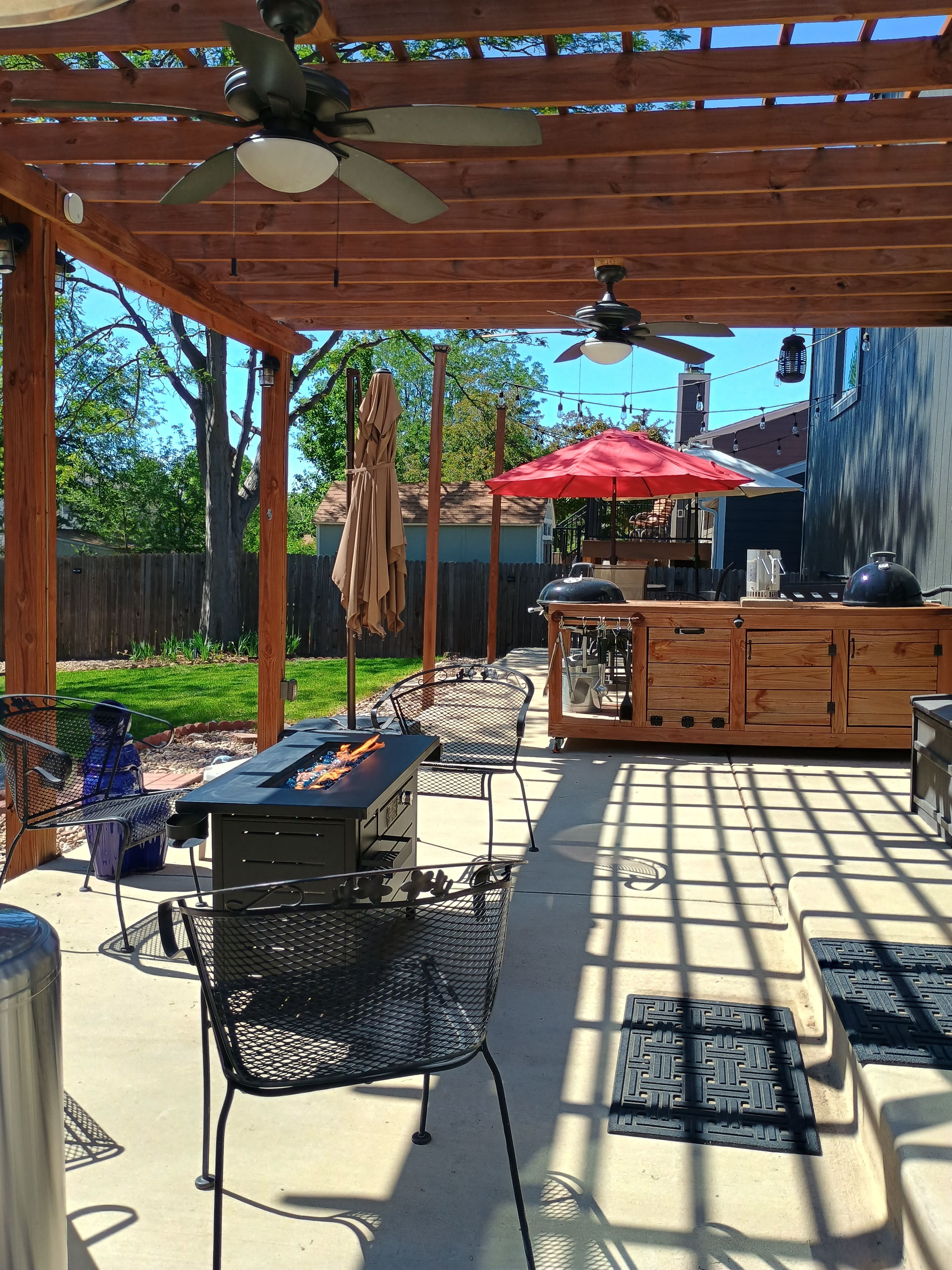 An outdoor patio with a grill, seating, and a ceiling fan.