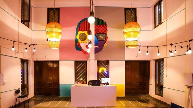A lobby with a reception desk, two hanging lamps, and a large abstract artwork on the wall. - THE PUNE STORY HOSTEL (Pune)