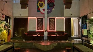 A lobby with a central seating area, a large wall mural, and hanging baskets. - THE PUNE STORY HOSTEL (Pune)