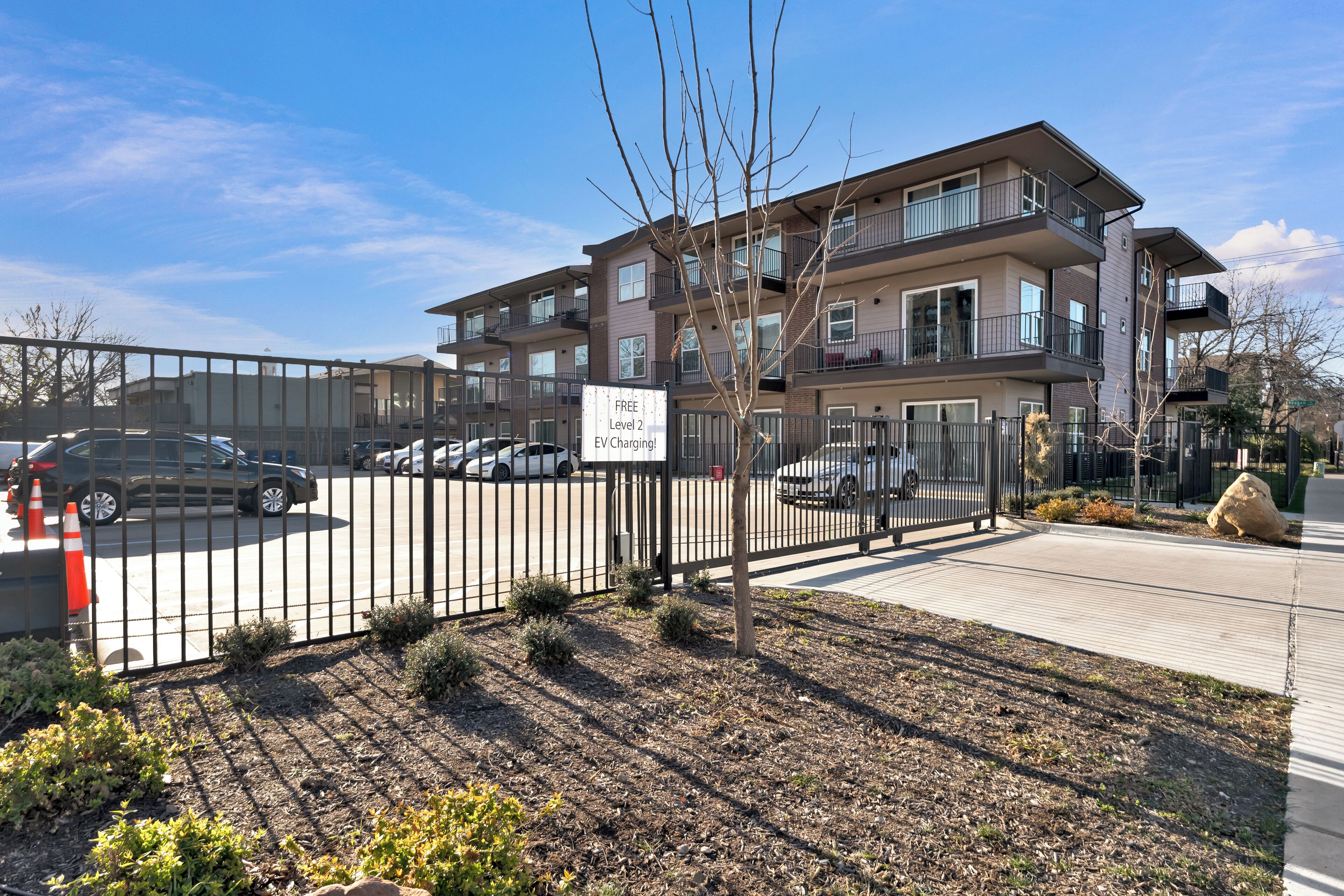A multi-story apartment building with a fenced parking area.