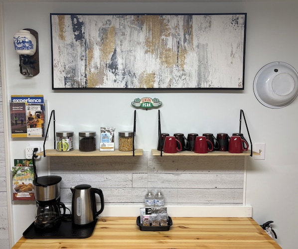 A kitchen with a coffee maker, kettle, and jars of coffee on the counter.