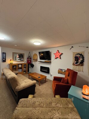 A living room with a sofa, armchair, coffee table, TV, and decorative items.
