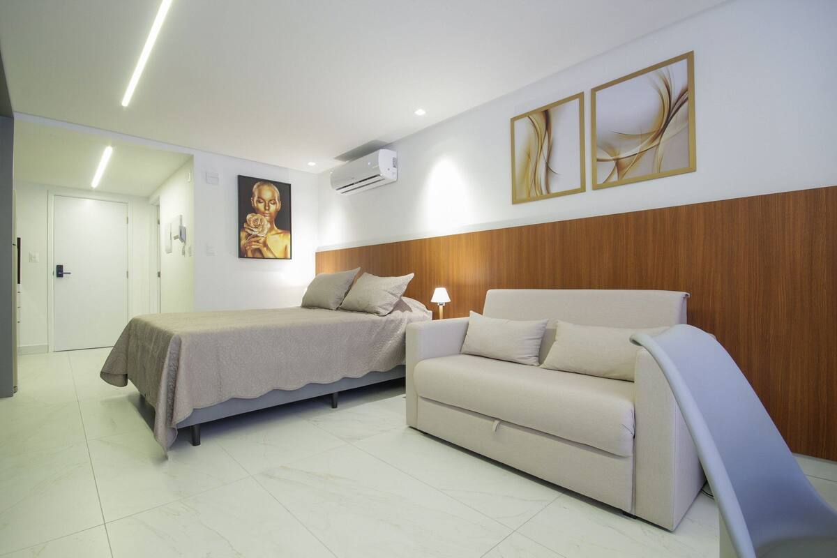 Une chambre à coucher avec un lit, un canapé et un climatiseur fixé au mur.