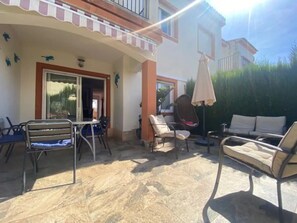 Eine Terrasse im Freien mit Tisch und Stühlen, einer Liege und einem überdachten Sitzbereich.