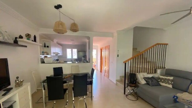 Een moderne woonkamer met een bank, televisie en een eethoek.