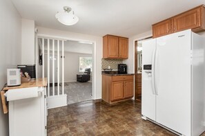 A kitchen with wooden cabinets, a white refrigerator, a coffee maker, and a countertop with a toaster.