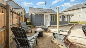 Un jardin avec des fauteuils Adirondack, un foyer et des guirlandes lumineuses.