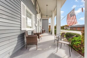 A covered porch with wicker furniture and an American flag.