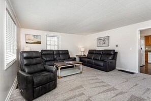 A living room with two black leather sofas, a wooden coffee table, and a carpeted floor.