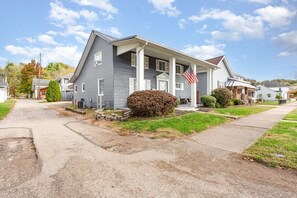 A two-story house with a front porch, a flag, and a well-maintained lawn.