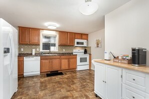 A kitchen with wooden cabinets, a microwave, a coffee maker, and a tiled backsplash.