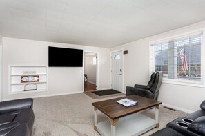A living room with a TV, a sofa, a coffee table, and a 'Welcome Home' sign.